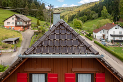 Krüppelwalmdach mit J11v in edelbraun auf saniertem Wohnhaus mit 3-achsige Walmkappe und Grad samt Anfänger im Bild.