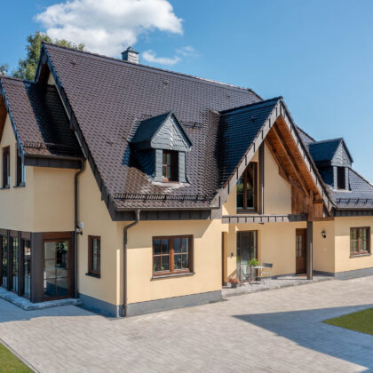 Biber Rundschnitt in edelmarone auf Walmdach/Satteldach eines Einfamilenhauses in der Gesamtansicht.