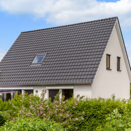 Klassisches Einfamilienhaus mit zeitlosem Flachdachziegel J11v in altschwarz mit toller Hecke.