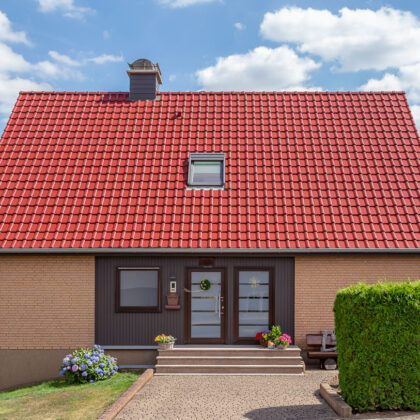 Strahlend rotes Dach kombiniert mit brauner Klinkerfassade