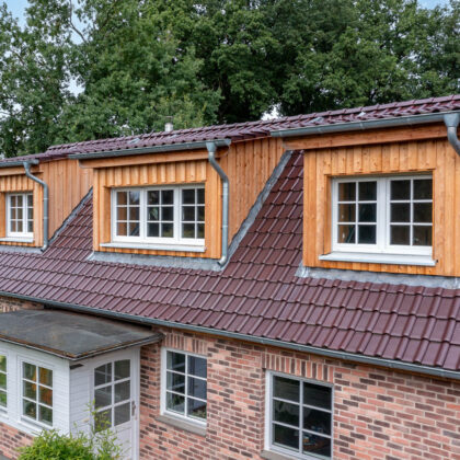 Glasur bordeauxrot matt auf Klinkerhaus mit Fokus auf die holzvertäfelten Gauben.