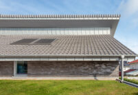 Side view of a trendy clinker brick house with J13v flat roof tile in silver-grey