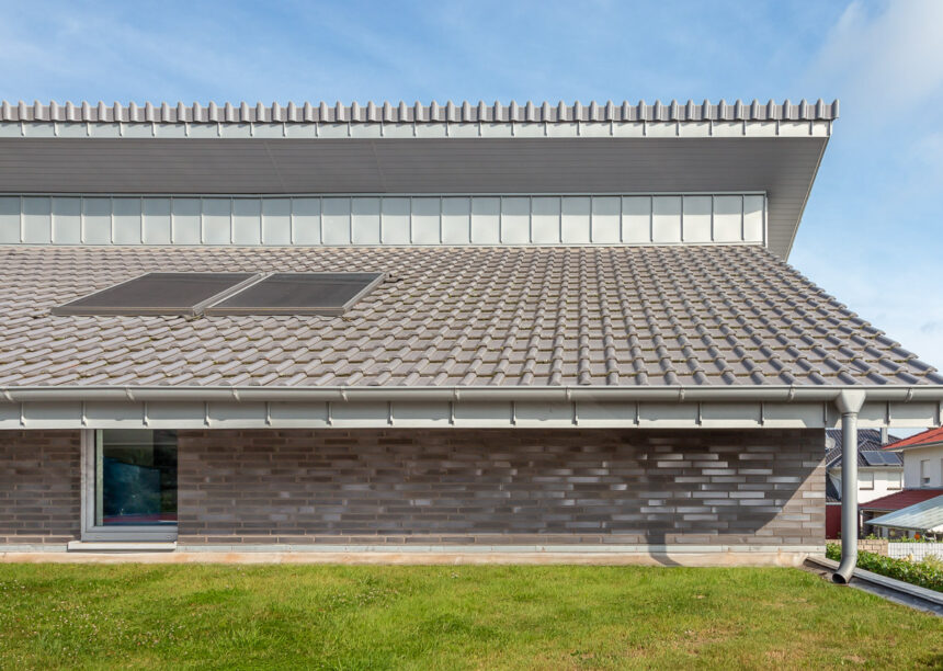 Side view of a trendy clinker brick house with J13v flat roof tile in silver-grey