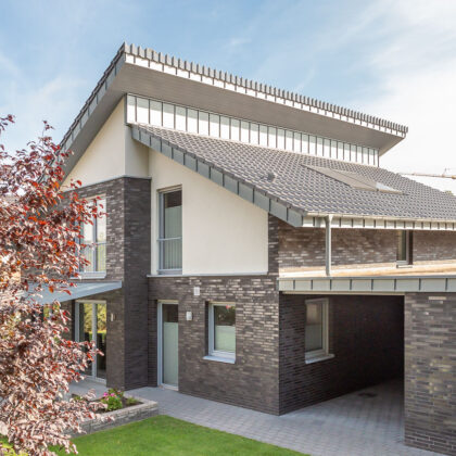 Modern detached house with mono-pitch roof, covered with silver-grey flat roof tile J13v