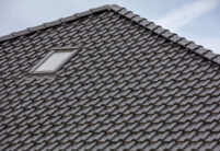 Detailed view of a roof covered with flat roof tile J13v in matt slate grey and ridge F6v