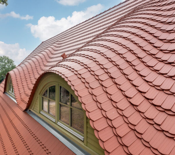 Berlin plain tile in natural red on a crested hip roof. The focus here is on the dormer and the crown covering.