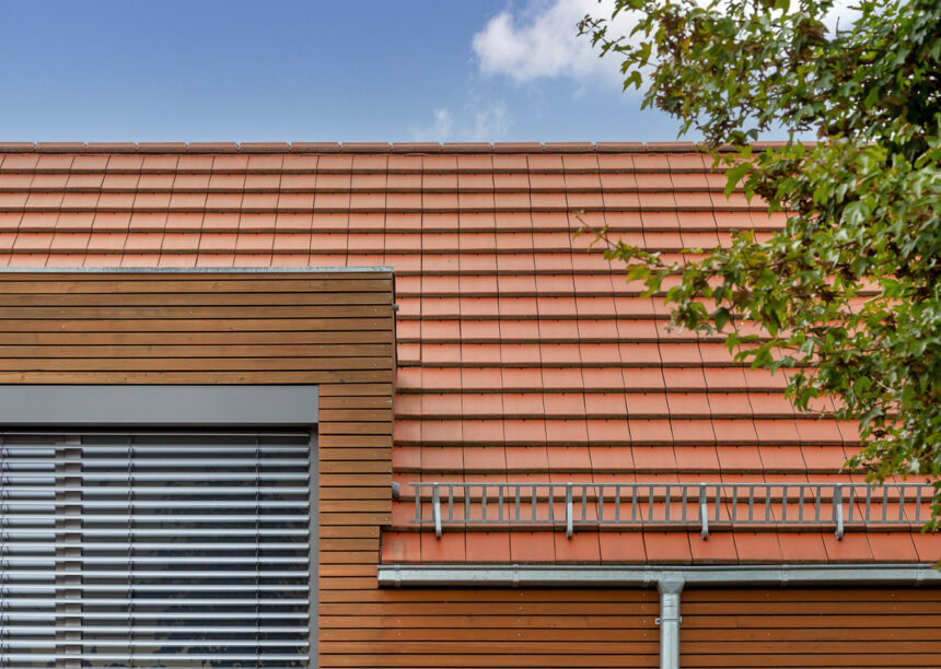 Detached house with wooden elements and the WALTHER Stylist flat tile in red-brown on the roof