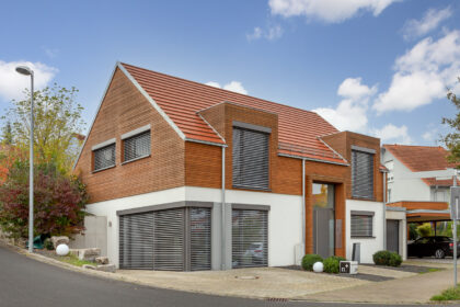 Detached house with wooden elements and the WALTHER Stylist flat tile in red-brown on the roof