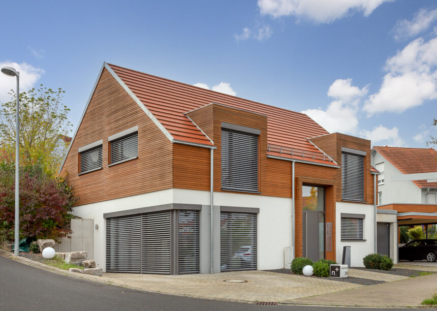 Detached house with wooden elements and the WALTHER Stylist flat tile in red-brown on the roof